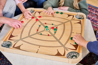 Hands on a carrom board as a game is played.