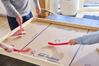 Hands in action while playing on a large nok hockey table.