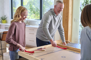 Adult and child play on the same team on a large nok hockey game board.