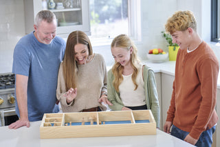 Parents and two children play on a skittles game board together.