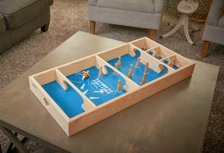 Carrom skittles board set up for gameplay on a coffee table.