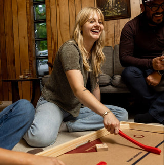 Woman and her friends playing on a Nok Hockey board for board game night. 